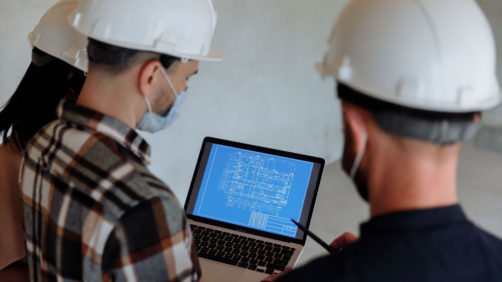 Equipo de consultores de Allstar con casco de seguridad revisando planos de cumplimiento normativo en obra